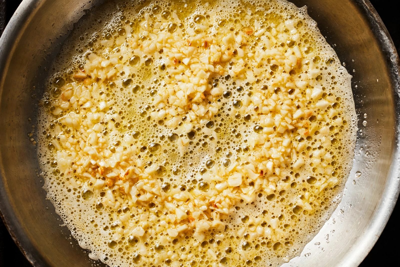 Minced garlic softening in melted butter in a skillet.