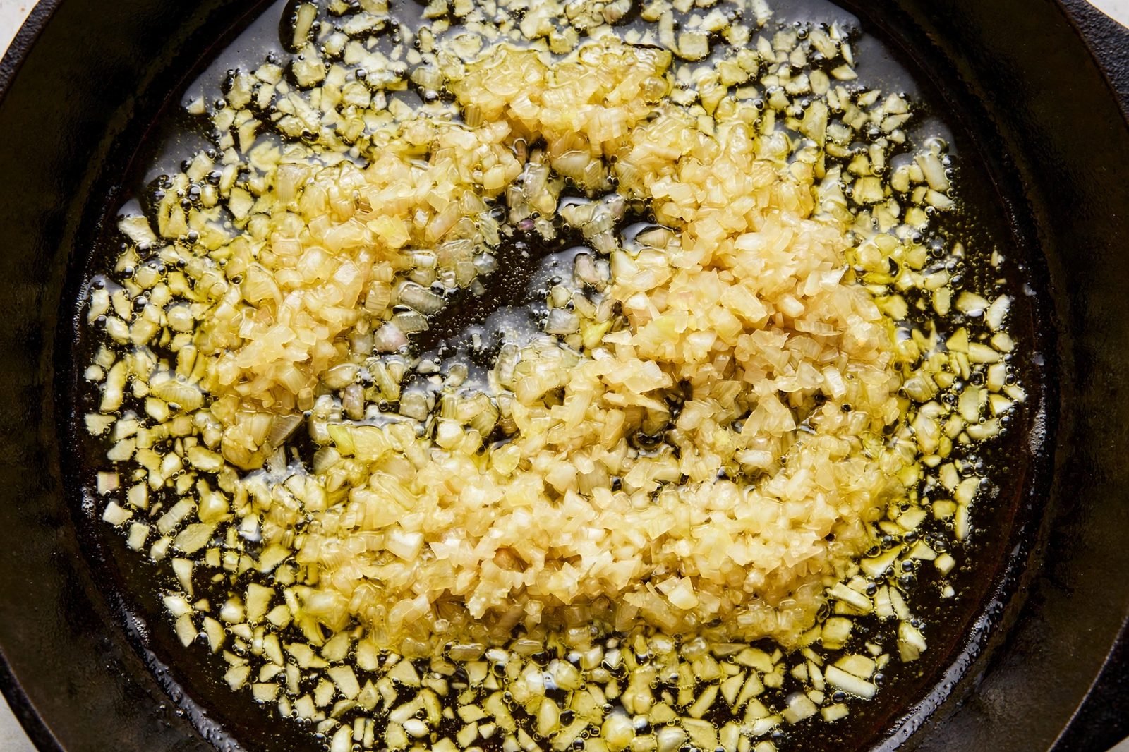 Overhead of minced shallot and garlic softening in the skillet.